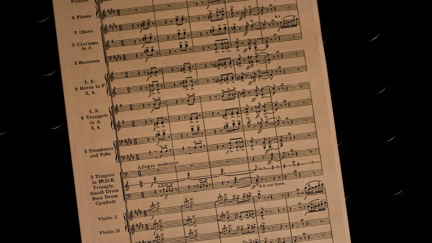 A page of orchestral score for flutes, horns, trumpets and violins against a black background