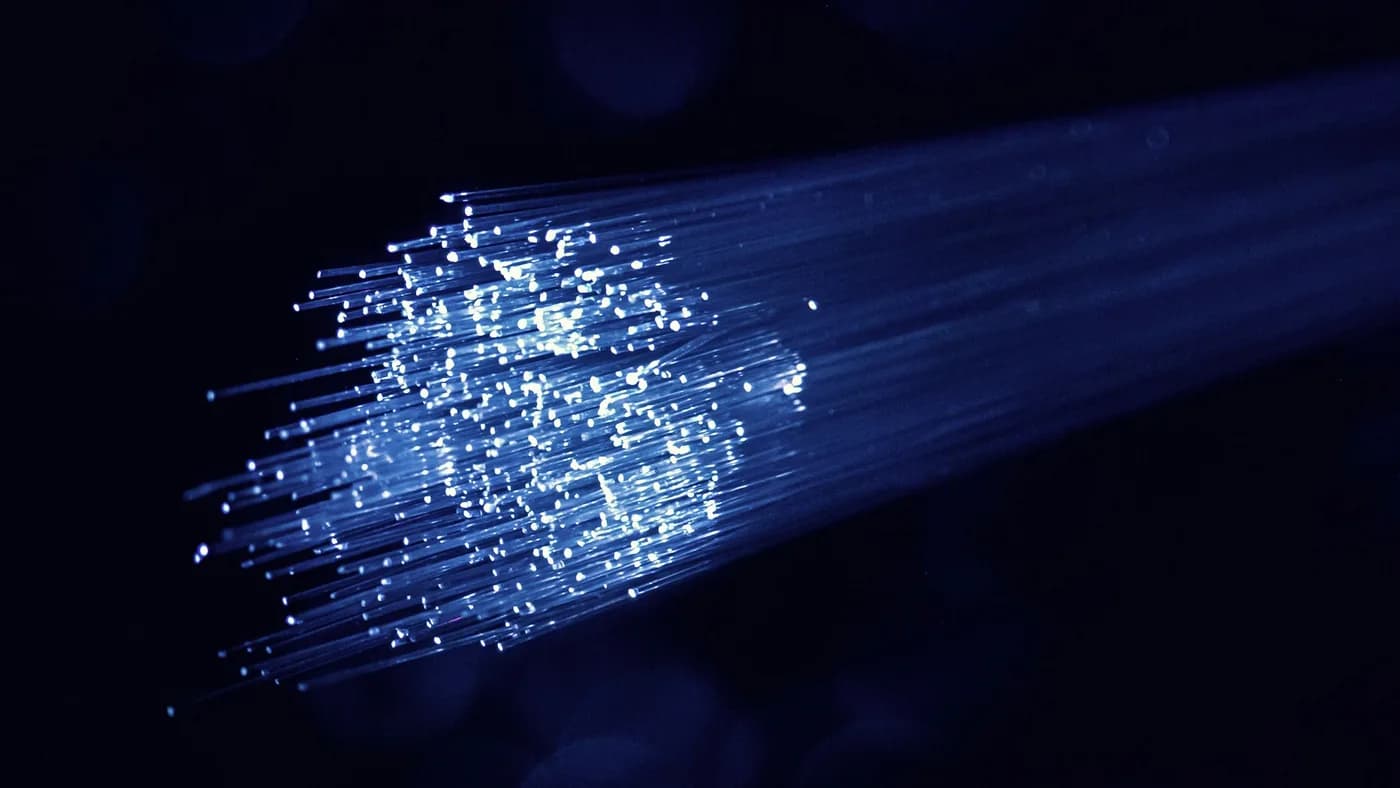 Bundle of fiber-optic strands glowing blue against a black background
