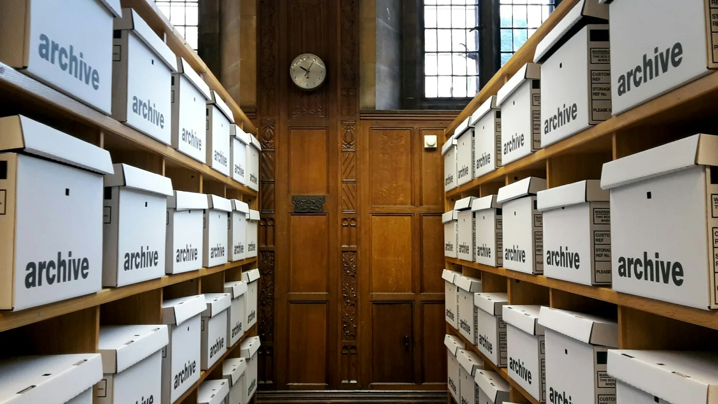Rows of white archive boxes on wooden shelves in a wood-panelled room