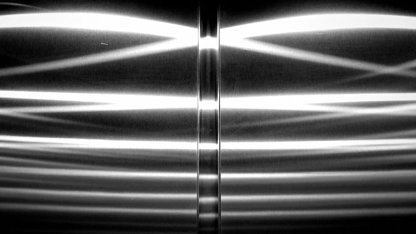 Bright horizontal light streaks mirrored across two brushed metal panels split by a vertical seam