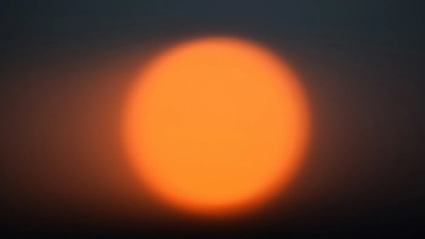 Blurred orange sun glowing against a dark slate sky