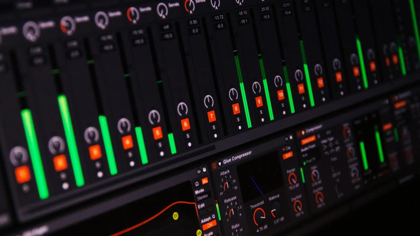 Close-up of a digital audio mixer on black, with green channel level meters at varying heights