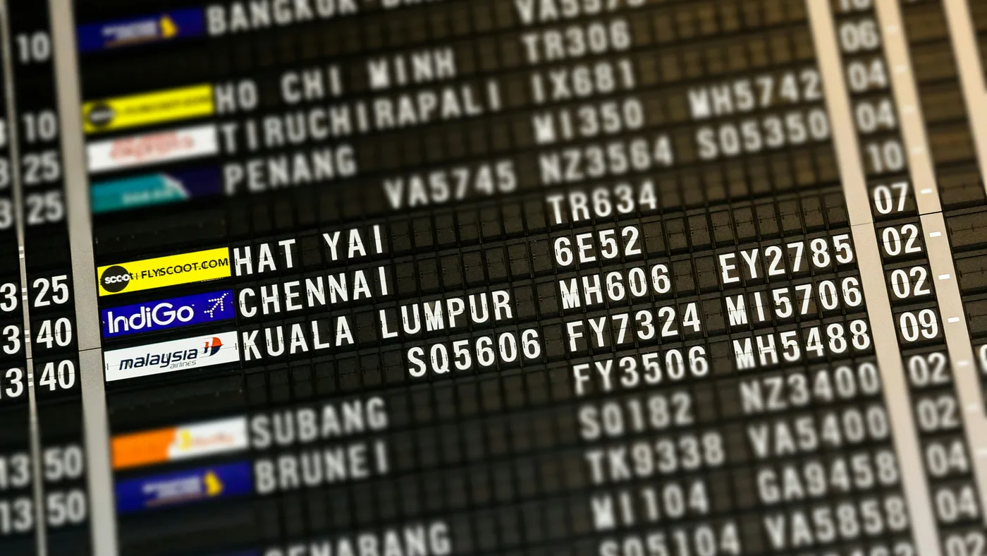 Close-up of a dark split-flap airport departure board listing destinations in white lettering