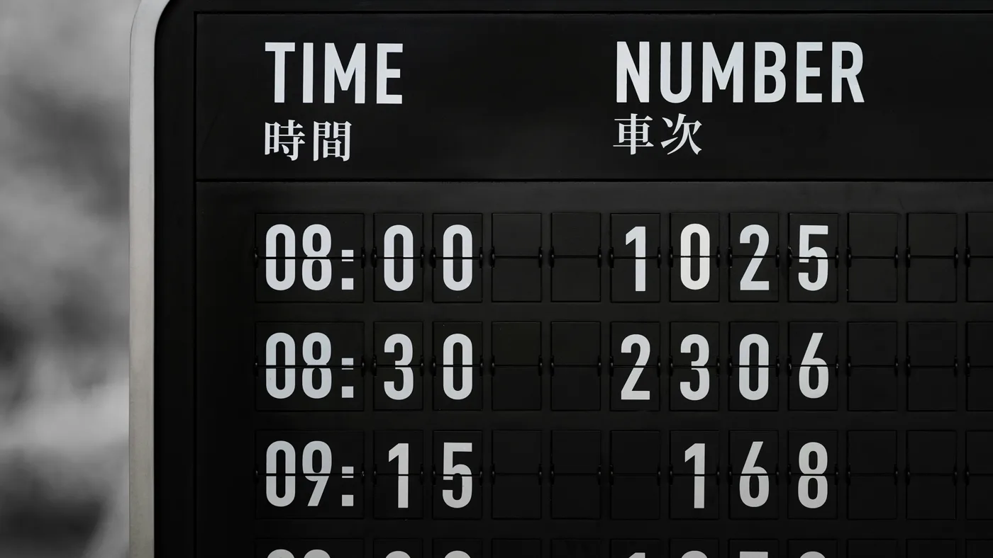 Black split-flap departure board listing scheduled times with train numbers beside them