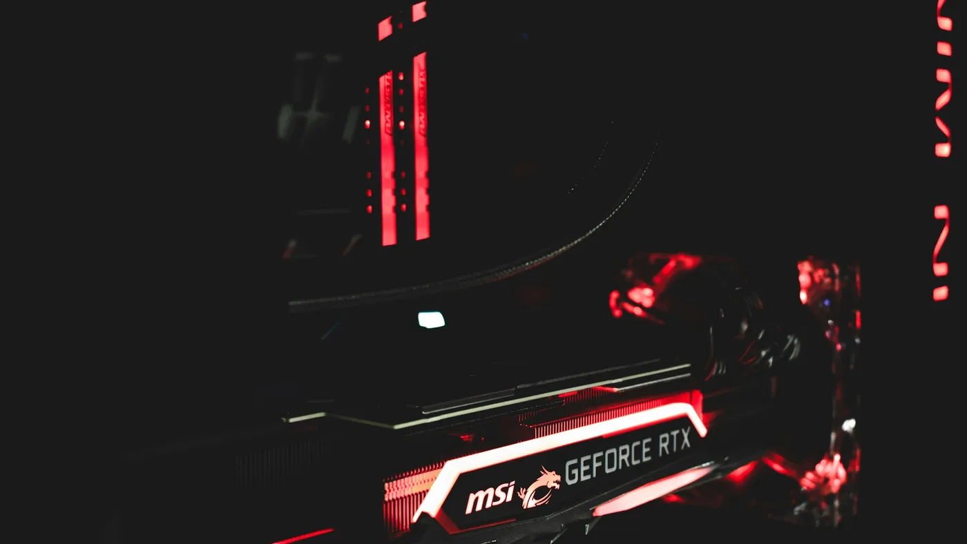 Close-up of a GPU glowing red inside a dark PC case, with RAM sticks lit in the background