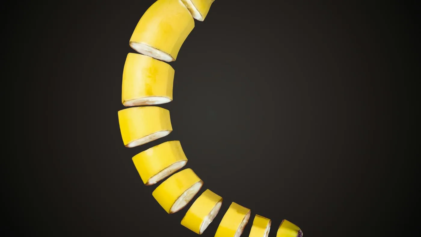 A yellow banana cut into slices, arranged in a crescent curve against a dark charcoal background