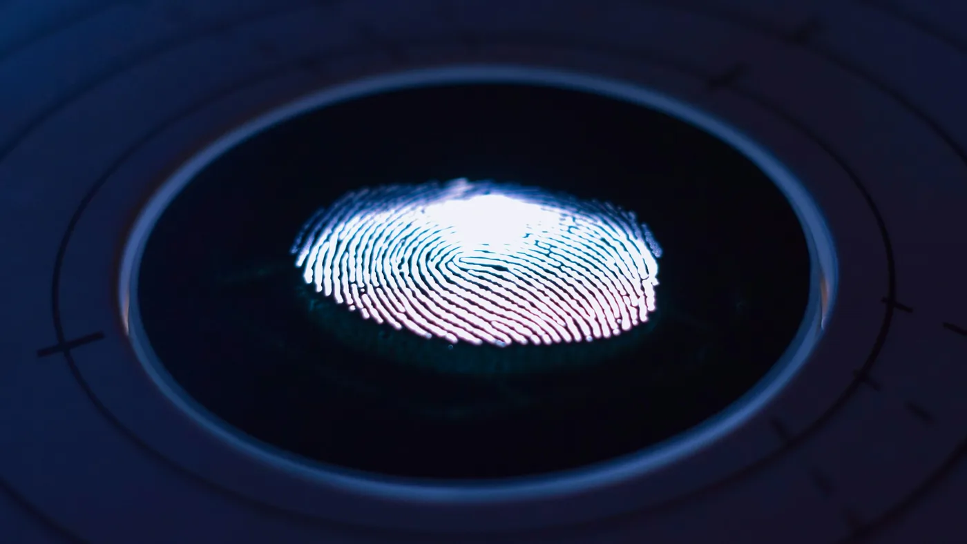 A glowing white fingerprint on a dark blue circular scanner lens with concentric rings