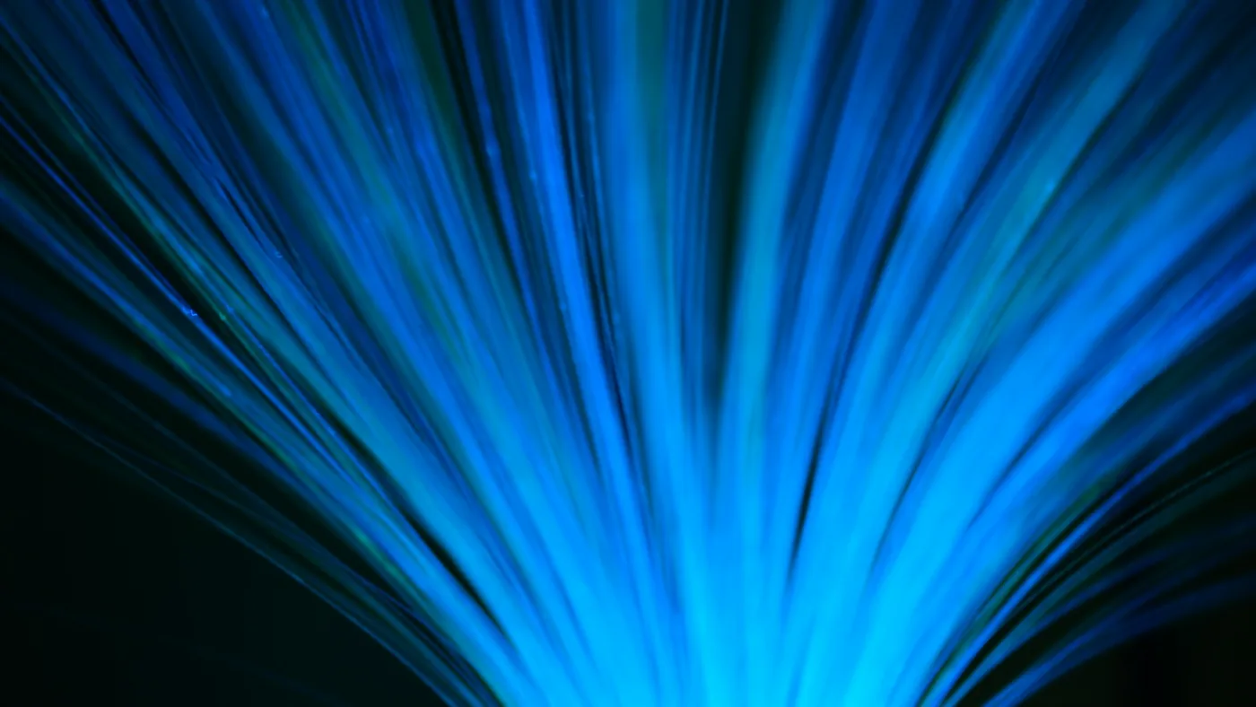 Abstract blue fiber-optic light strands on a dark background representing token throughput