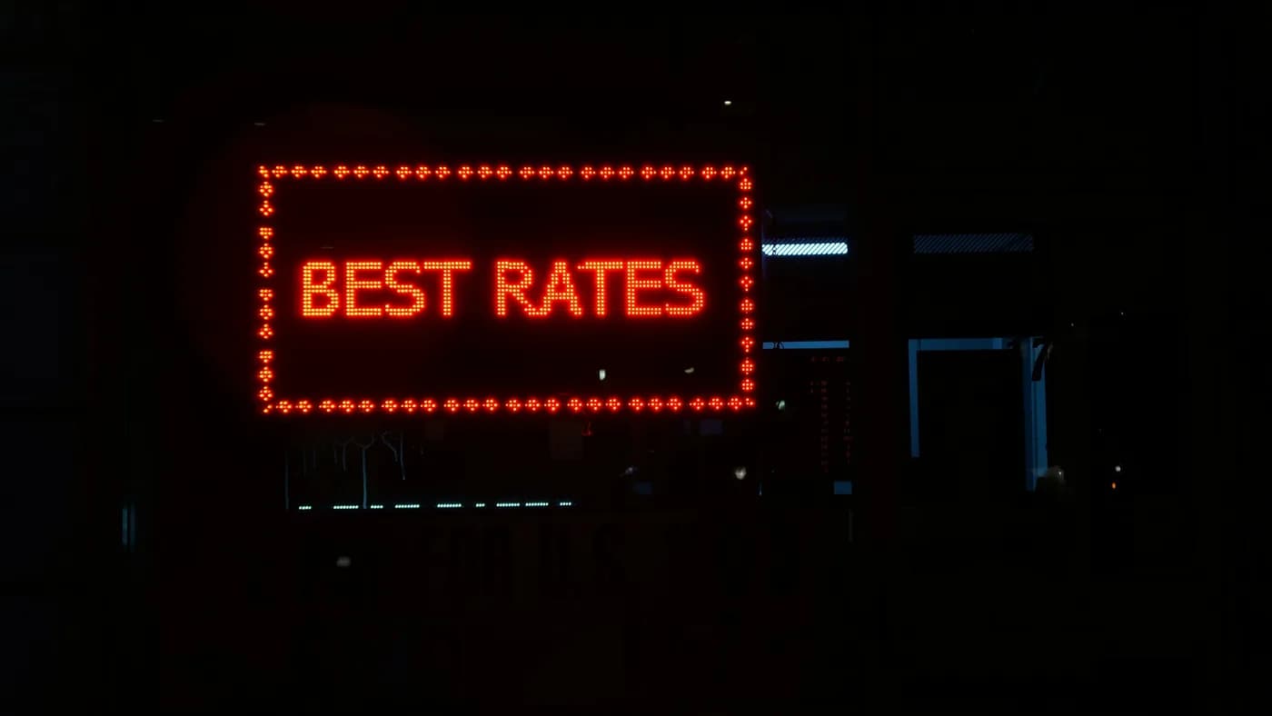 Red LED BEST RATES currency exchange sign glowing in a dark shop window at night