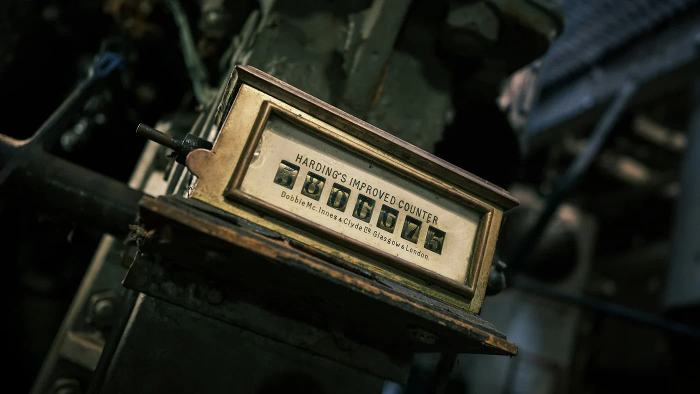 A worn brass mechanical tally counter on industrial machinery, reading over five million