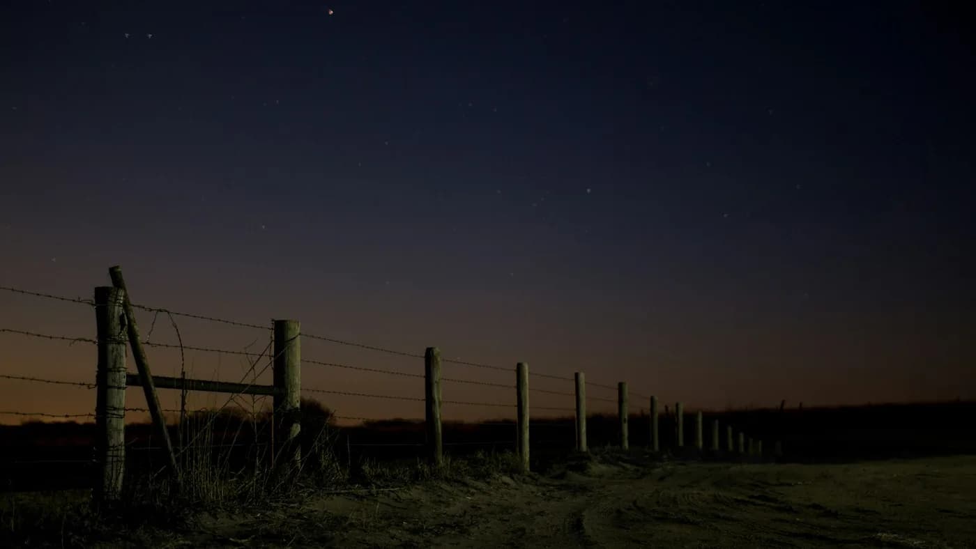 A boundary fence at night, standing in for US export gates on frontier AI models