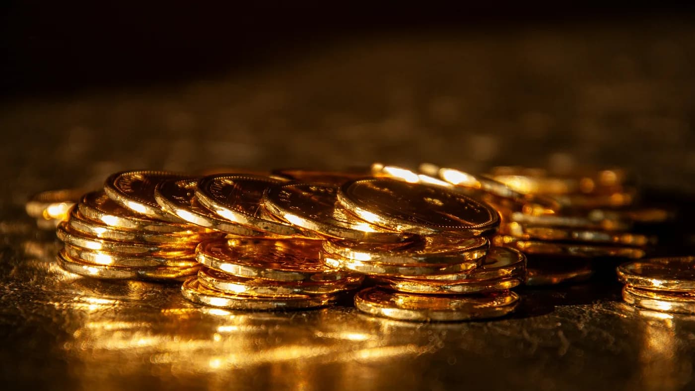 Stacks of gold coins glowing under warm light on a dark surface