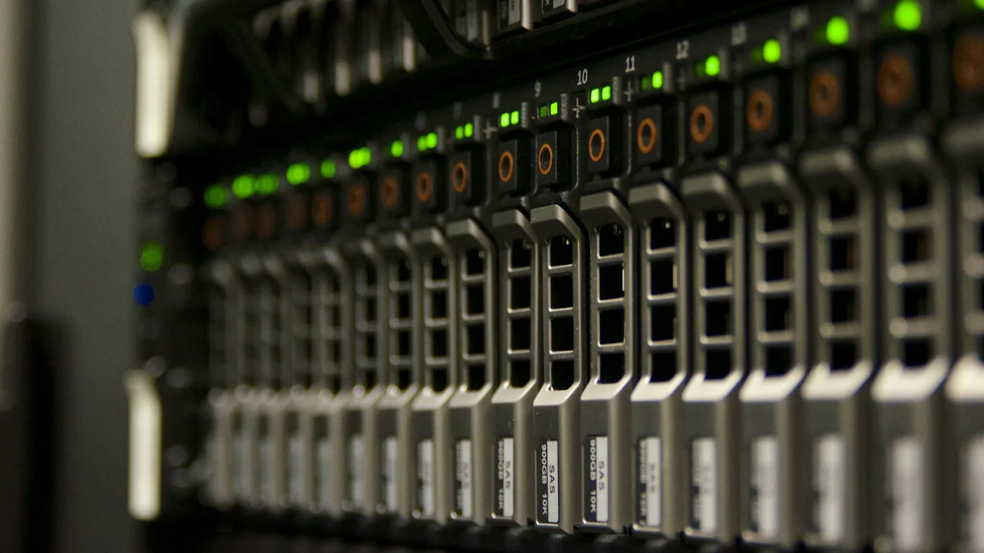 Rows of server drive bays with green and amber status lights receding into darkness